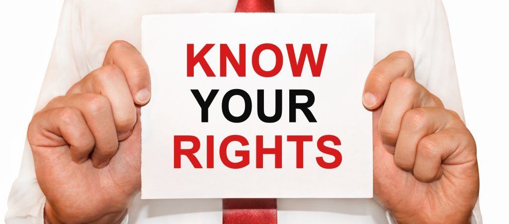 man in red tie holding "know your rights" sign