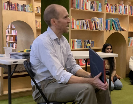 Headshot of Author Dan Swanson holding a book and reading it to a group of kids in a library.